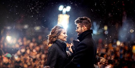 Young beautiful couple in love dancing in the city under snowfall on valentine's day