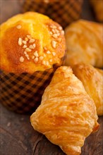Fresh baked muffin and croissant mignon on old wood table