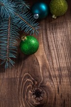Branches of fir tree and christmas baubles on vintage wood board
