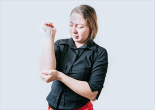 Young woman with elbow pain isolated. Woman with pain rubbing her elbow isolated. Arthritis and rheumatism concept