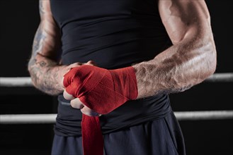 Red bandages on the hands of a kickboxer against the background of the ropes of the ring. The concept of mixed martial arts. MMA