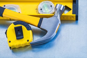 Construction level Measuring tape and claw hammer on metallic background Maintenance concept