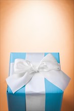 Blue gift box with white ribbon on a light brown background with Copyspace