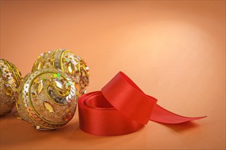Golden Christmas baubles and red bow on a brown background