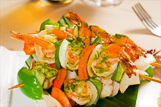 Fresh and colorfull grilled shrimps and vegetables skewers on a palm leaf