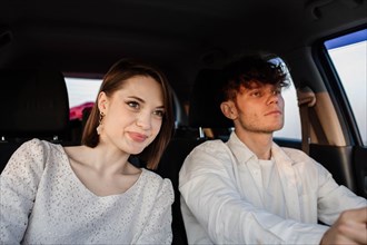 Positive couple in love ride in a car on a trip to a date on a sunny day