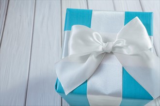 Blue gift box with white ribbon on a white wooden table