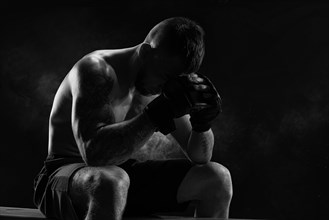 Kickboxer with overlays on his hands prays before the fight. The concept of mixed martial arts. MMA