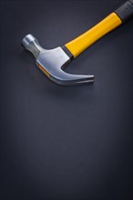 Close-up of a claw hammer with yellow and rubberised handle on a black background