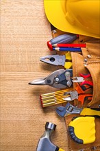 Construction tools in tool belt Hammer Punch pliers Pliers Cutter Pencil Screwdriver Helmet on wooden board