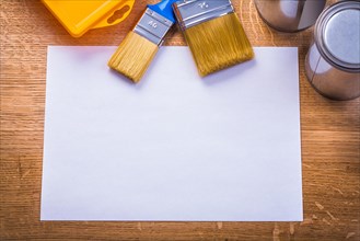 Painting utensils on wooden board and blank white paper