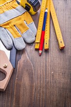 Composition of carpentry tools handw glove tapeline wooden metre pencil on vintage board construction concept