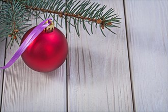 Copyspace image red Christmas bauble and fir tree branch on white wooden boards