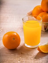 Glass with juice and oranges on wooden board