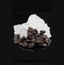 Crystal sugar and coffee beans over black reflective surface background