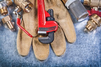 Composition of plumbing brass hardware leather safety gloves on metallic background construction concept