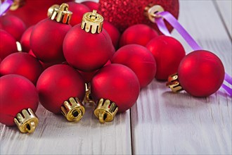 Close up view of stack of red Christmas baubles on wooden boards horizontal version