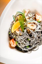 Fresh seafood black squid ink coulored spaghetti pasta tipycal italian food