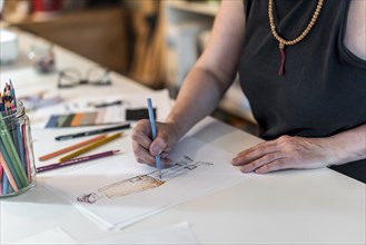 High angle of a fashion designer drawing a fashion sketch with colorful pencils