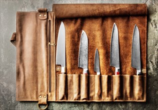 Japanese knives of different sizes from Damascus steel are in a leather case. Business concept of career growth