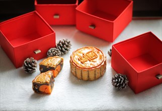 Traditional mooncakes and pinecones set against red gift boxes