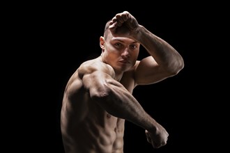Professional boxer posing in the studio. He stands in front of the camera and elbows. The concept of sport