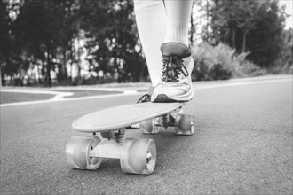 Images of a leg standing on a skateboard. Sunny evening in the park. Skateboarding concept.