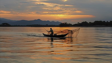 A solitary fisherman manages his net on a boat against the backdrop of a serene sunset
