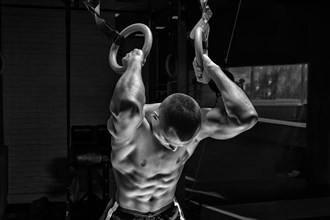 Athlete does warm-up on gymnastic rings. The concept of sport and healthy lifestyle.