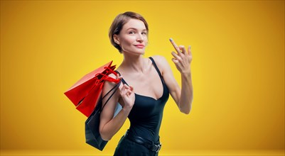 Portrait of a beautiful woman with red packages. She shows a fuck sign and smiles. Shopaholic concept. Shopping centers. Sales.