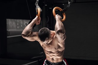 Athlete does warm-up on gymnastic rings. The concept of sport and healthy lifestyle.