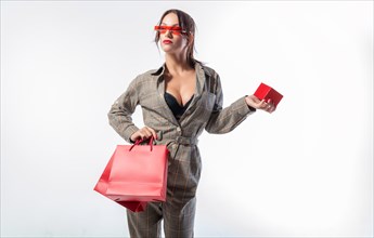 Charming brunette in glasses posing in the studio with red bags and a box for jewelry. White background. Shopping concept.