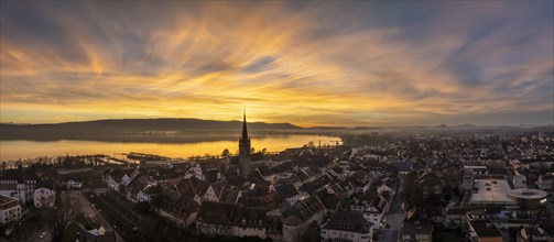 Aerial panorama of an atmospheric sunset over the old town of Radolfzell on Lake Constance with the cathedral tower