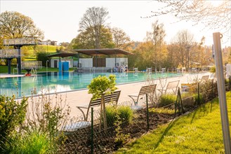 Empty outdoor pool with wooden benches and a fence in the beautiful evening light