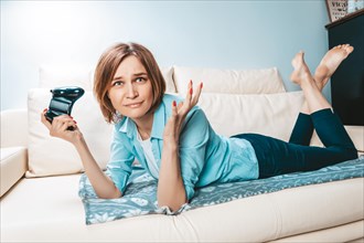 Girl with a joystick in her hands lies on the couch and plays a computer game. ESports concept.