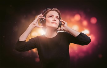 Image of a girl in a black dress with headphones in a nightclub. Party concept.