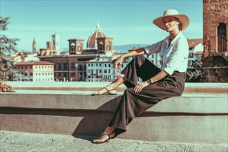 Portrait of a charming girl sitting near a fountain in Florence. View of Santa Maria del Fiore. Tourism concept. Italy.