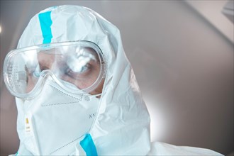 Medical laboratory assistant in a chemical protection suit and safety glasses