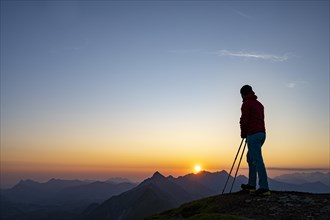 Mountaineer on mountain ridge with Rothorn peak in the background at sunrise