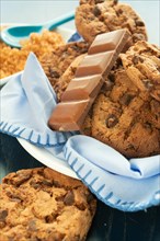 Close-up of chocolate chip cookies and a chocolate bar on a blue napkin