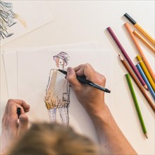 Top view of a fashion designer drawing a fashion sketch