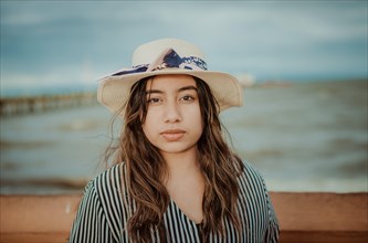 Portrait of beautiful latin girl in hat on the pier. Portrait of young tourist woman in hat on a pier