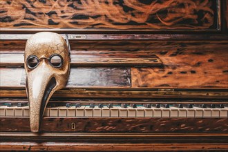 Abstraction of a venetian mask of a doctor lying on the piano keys. Concept of epidemic