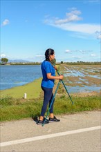 Active individual with walking poles next to a water body on a sunny day
