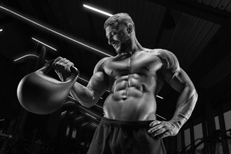 Muscular man posing in the gym with a kettlebell. Fitness concept.