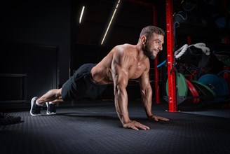 Muscular man doing push-ups in the gym. Fitness concept.