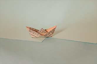 A simple origami paper boat on a diagonal split background with blue hues