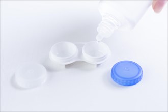 Liquid for lenses is poured into the boxes. Ophthalmology concept. White background.