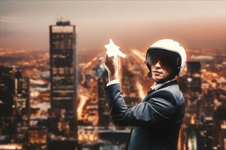 Portrait of a man in a suit and helmet. He launches a paper airplane from the roof of a skyscraper. Business concept.