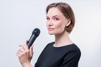 Portrait of an elegant stylish woman with a microphone. White background. Karaoke concept.